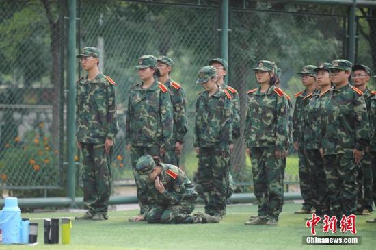 资料图：一名女同学在军训队伍中感到不适，跪在地上休息。 韦亮 摄