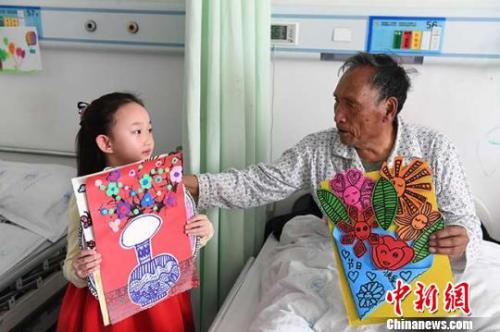 图为6岁的小女孩赵晋艺为病房里的老人送画。　杨艳敏　摄