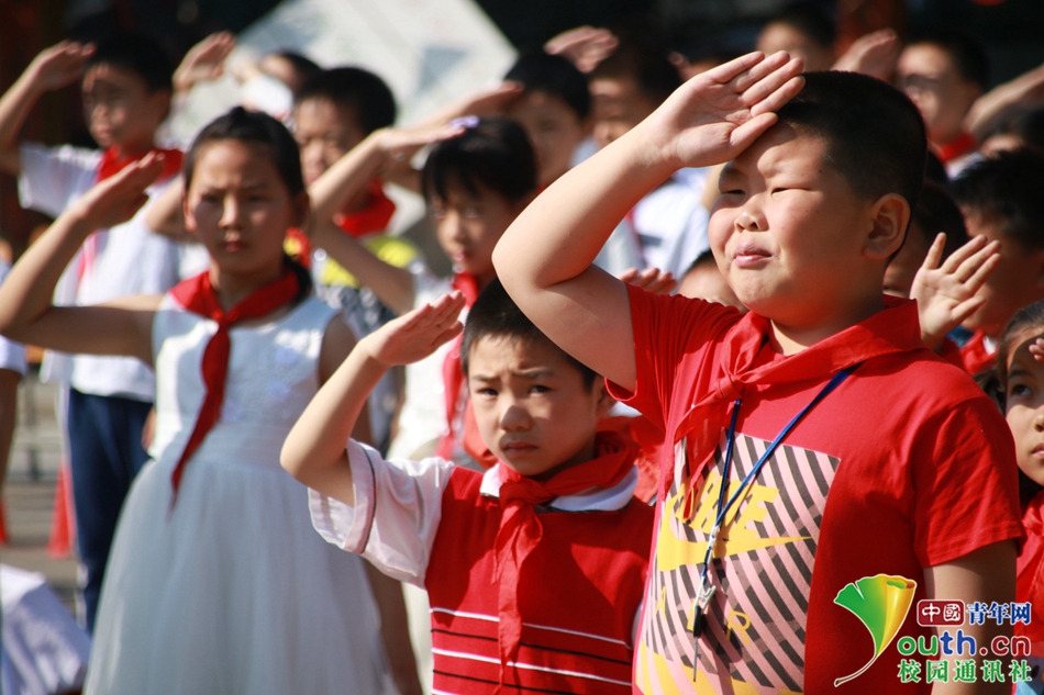 国歌响起,国旗飘扬,小学生在阳光下庄严地对国旗行注目礼.