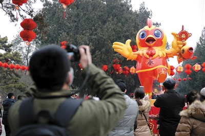 28日，游客在拍摄地坛庙会鸡年吉祥物。