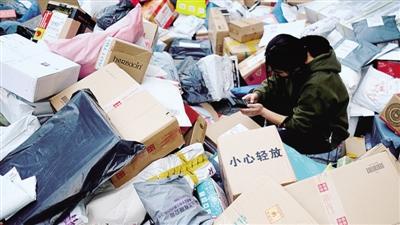 郑州大学的快递取件点，工作人员正在对卸了一地的快递进行扫码入库。