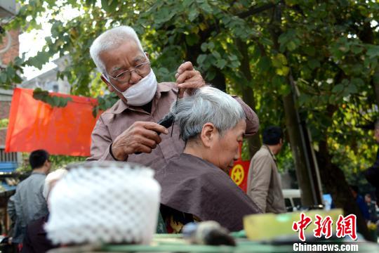 3月10日，75岁的志愿者韦天华正在市民提供免费理发服务。　孙赟飞 摄