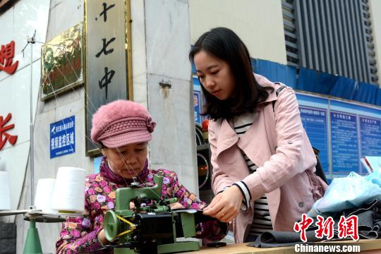 3月10日，广西柳州机车车辆厂的一对母女韦美京和池婷婷为市民提供免费衣物锁边服务。　孙赟飞 摄